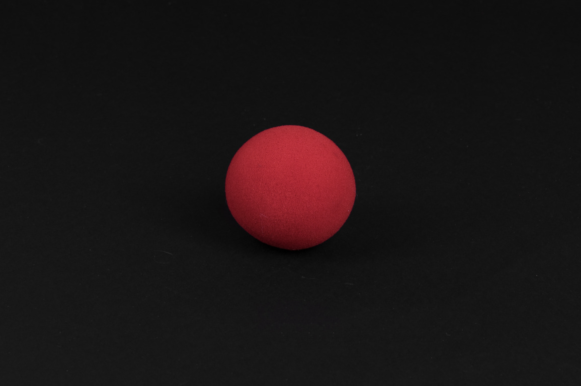 Picture of a red clown nose on a black background.